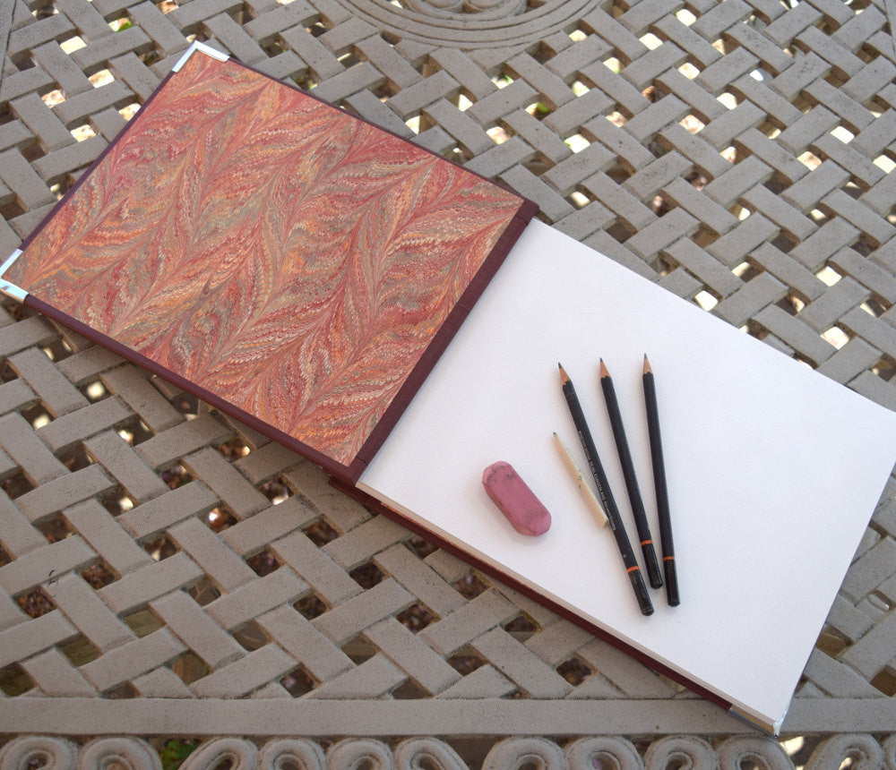 sketchbook open to display facing marbled paper and sketch pages