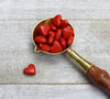 closeup of red wax hearts in brass spoon